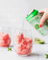 watermelon granita in wine glass with lime seltzer water being poured into it