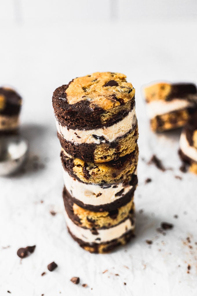 three ice cream cookie sandwiches stacked on top of each other with chocolate chips scattered around