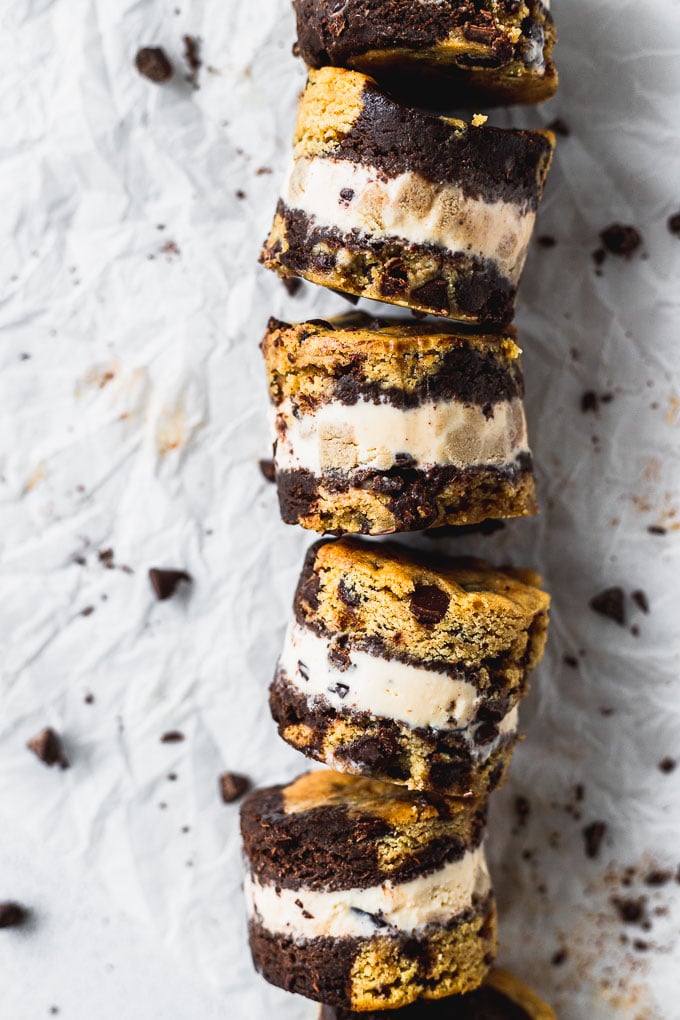 brookie cookie dough ice cream sandwiches laying on their side in a row on parchment paper