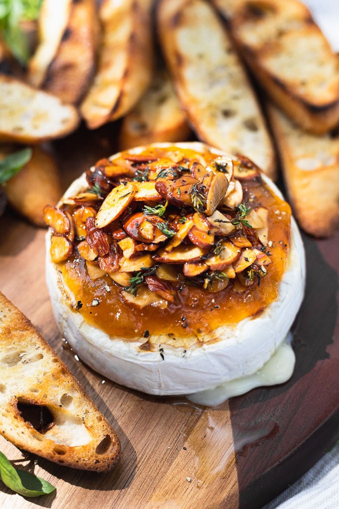 up close brie topped with apricot jam, almond slices, thyme, and honey