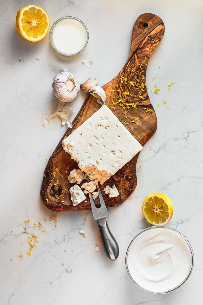 feta block on wood tray with garlic, lemon, and yogurt