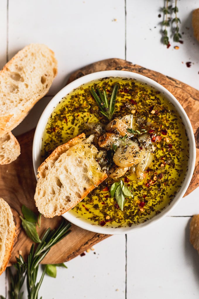 Plate of olive oil dip with roasted garlic and bread.