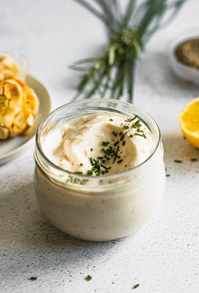 jar of garlic aioli from side with chives on top