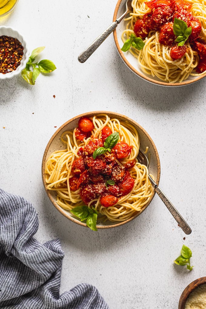 two bowls of spaghetti topped with tomato sauce and basil