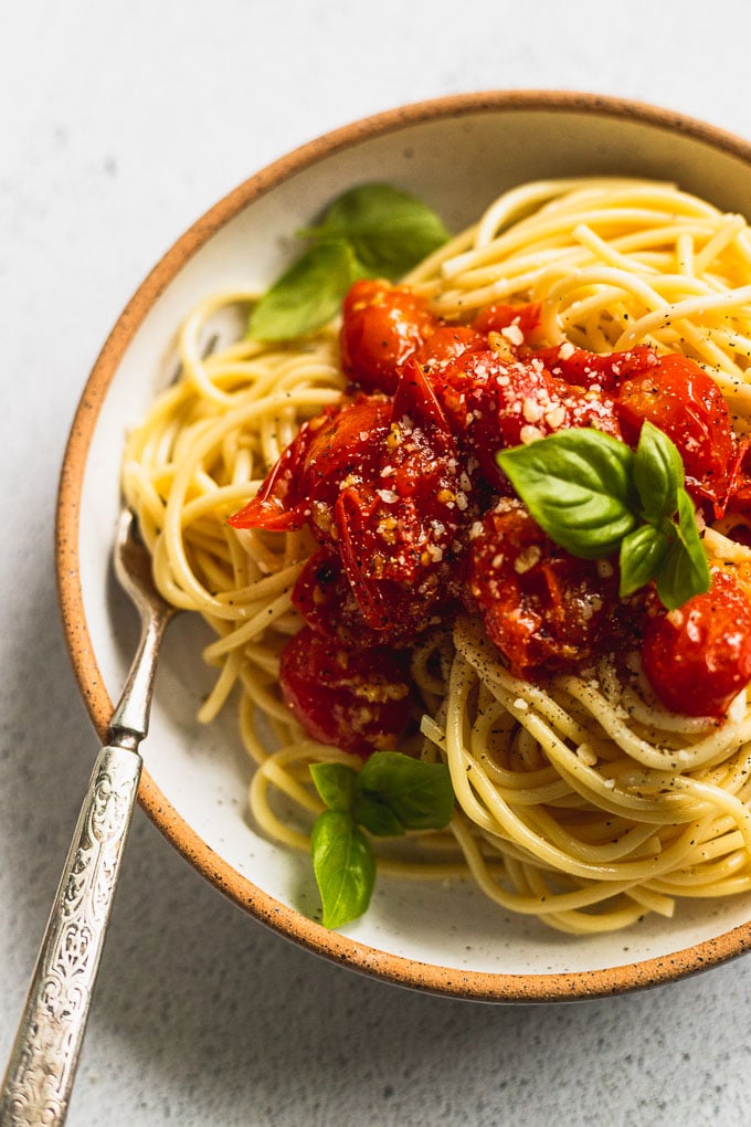 bowl of spaghetti with cherry tomato sauce and basil with a fork