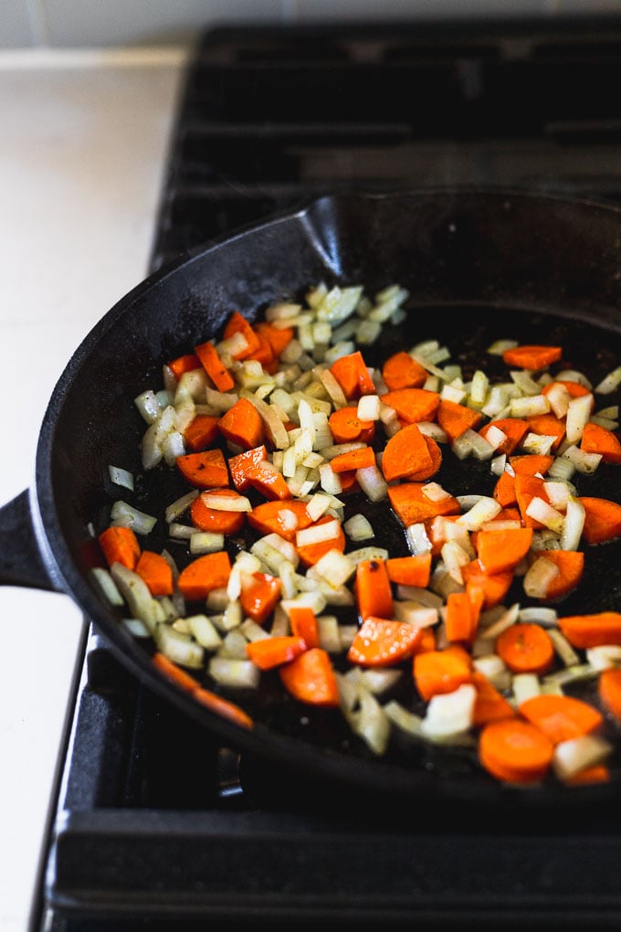 onion and carrots cooking in cast iron skillet