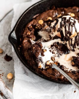 peanut butter brownie skillet with spoon and bite on it with melted ice cream