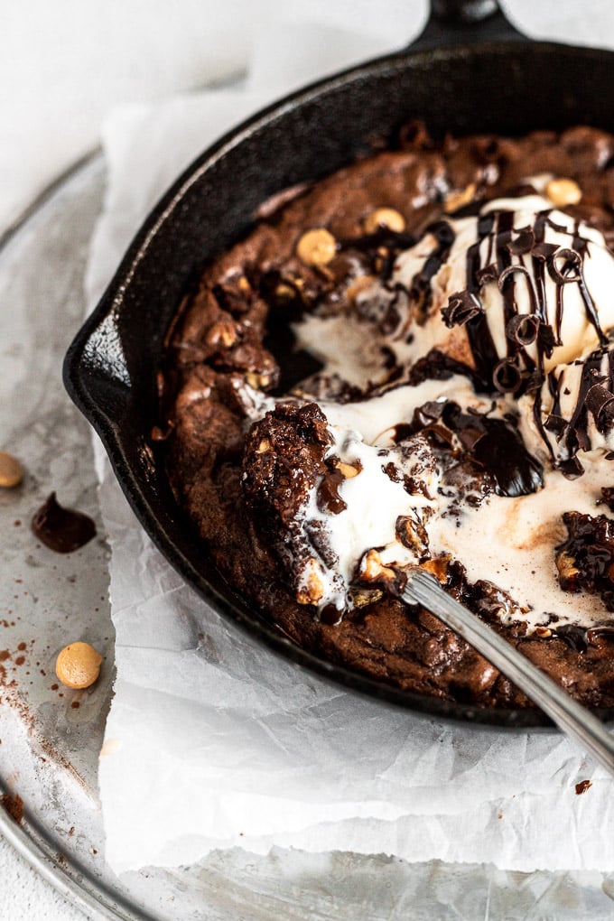 peanut butter brownie skillet with spoon and bite on it with melted ice cream