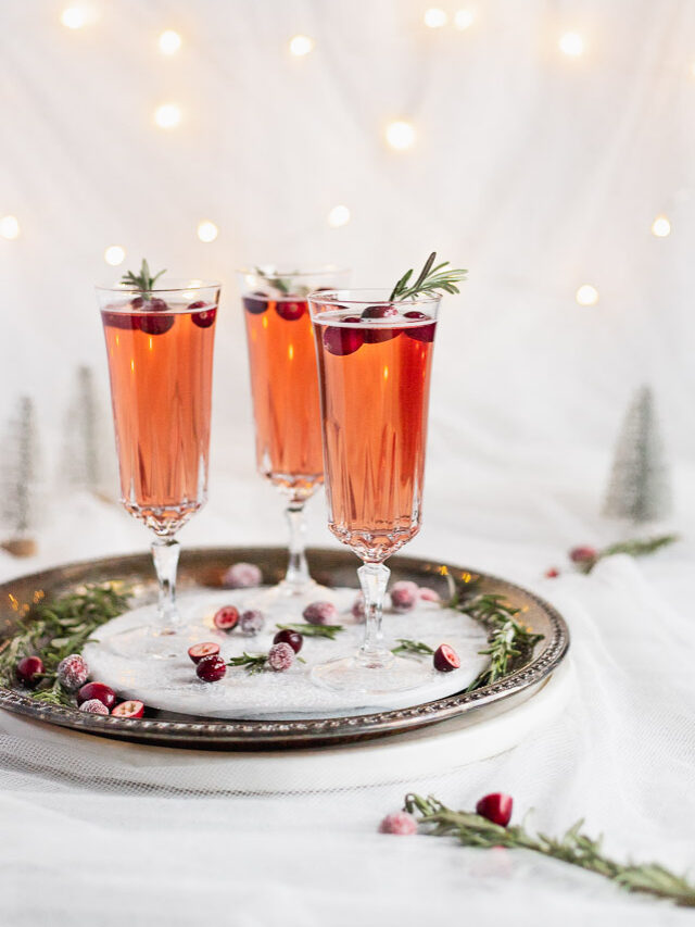 side view of cranberry prosecco on serving tray with rosemary sprig