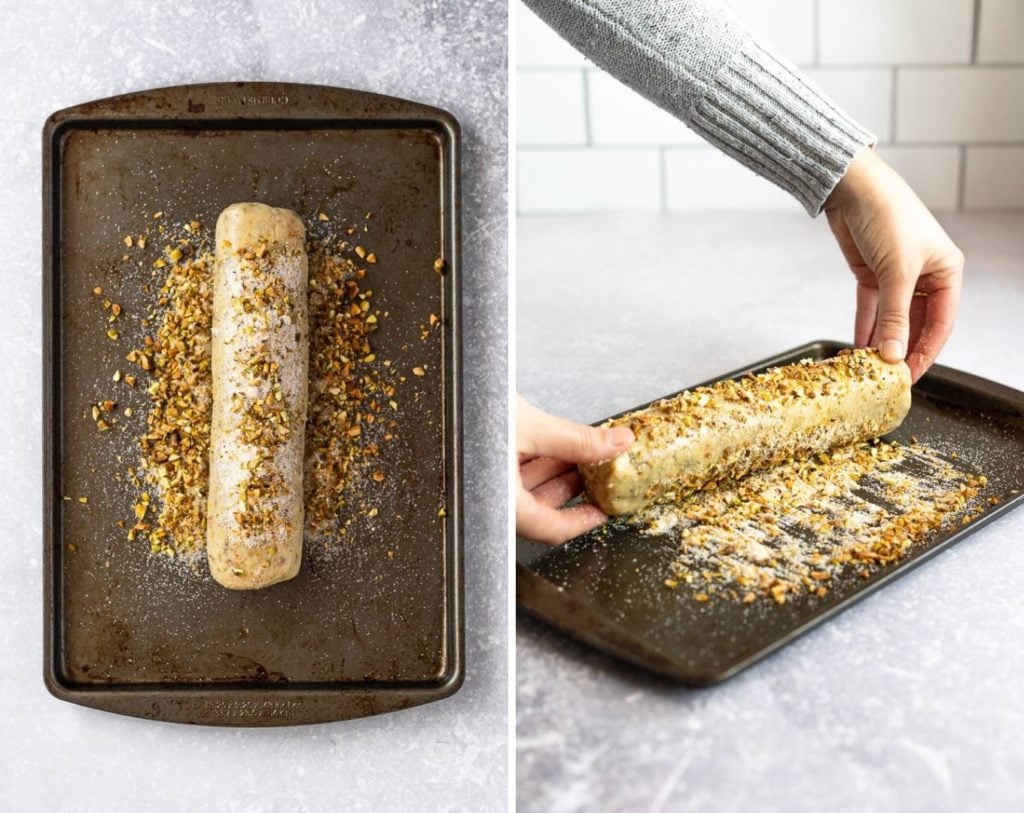 Pistachio butter cookie dough log on baking sheet rolling in pistachio mixture.