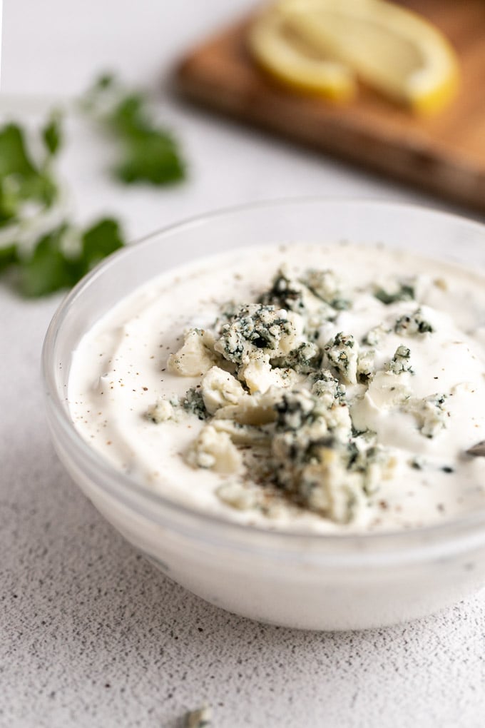 blue cheese crumbles on top of a bowl of blue cheese dressing