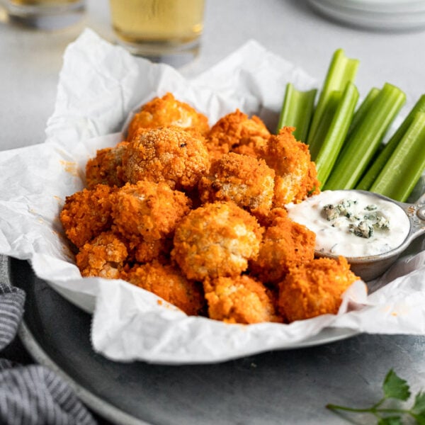serving tray with buffalo cauliflower bites next to celery and blue cheese