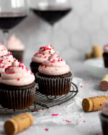 red wine cupcakes on cooling rack with wine glasses and corks
