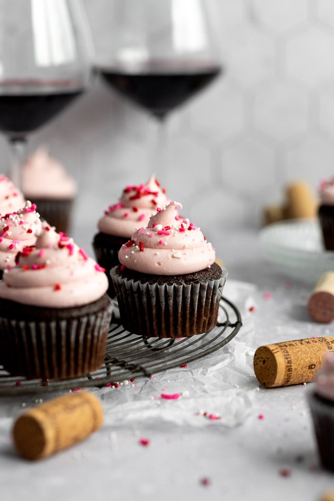 red wine cupcakes on cooling rack with wine glasses and corks