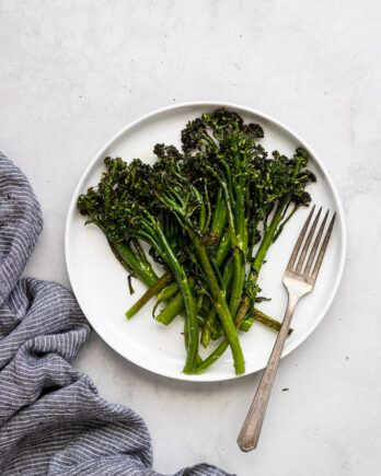 roasted broccolini on white plate with fork