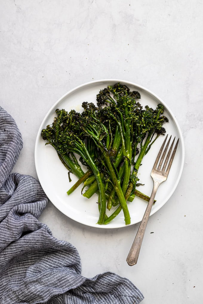 roasted broccolini on white plate with fork