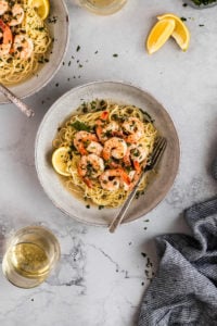Bowl of shrimp picatta with angel hair pasta with fork.