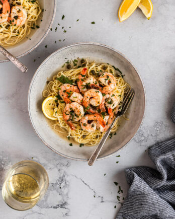 Bowl of shrimp picatta with angel hair pasta with fork.