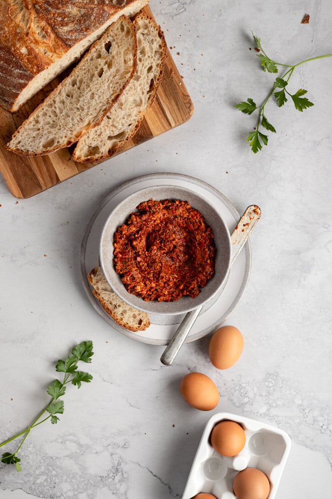 bowl of romesco next to sliced bread and eggs