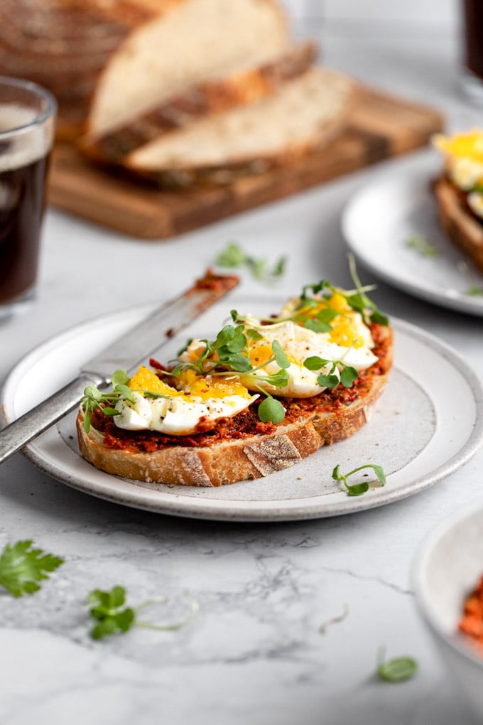 toast with romesco and a smashed egg with microgreens on gray plate