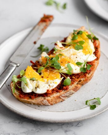 Romesco on toast topped with soft boiled egg and microgreens.