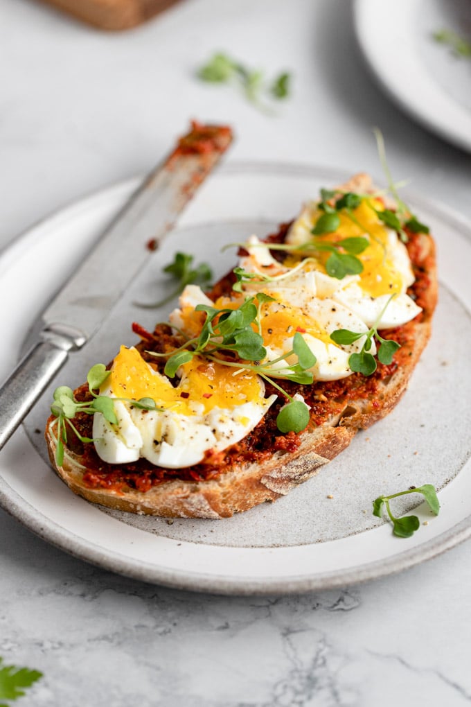 Romesco on toast topped with soft boiled egg and microgreens.