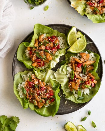 Plate of three lettuce wraps next to lime wedges and another plate.