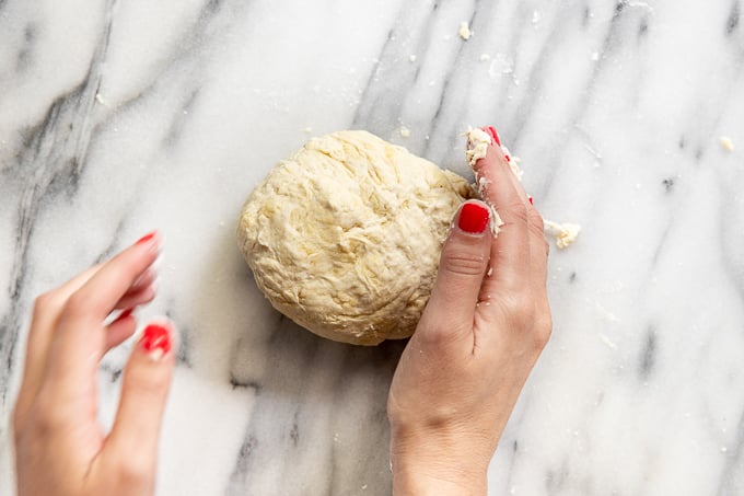 Hands shaping dough.