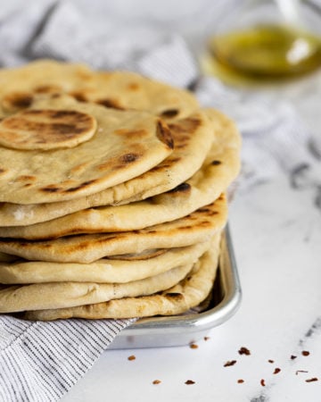 stacked flatbreads on metal tray with linen.