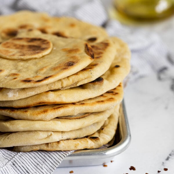 stacked flatbreads on metal tray with linen.