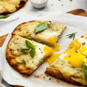 Slices of breakfast pizza with runny egg yolk.