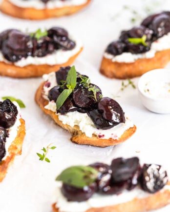 Roasted cherry crostini on parchment paper.