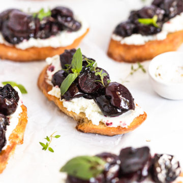 Roasted cherry crostini on parchment paper.