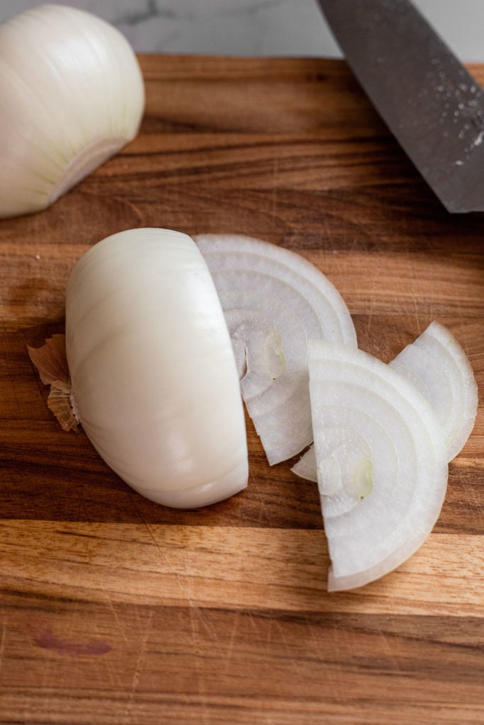 Onion on cutting board, thin slices.