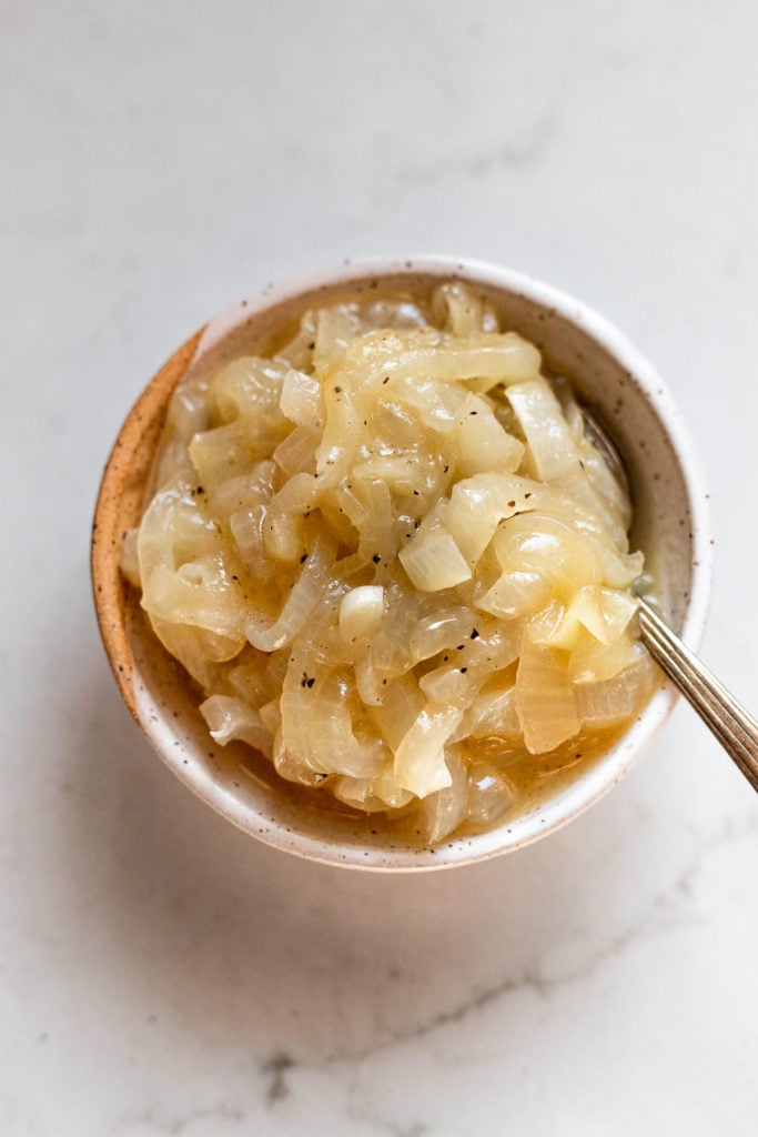 Bowl of caramelized onions with spoon.