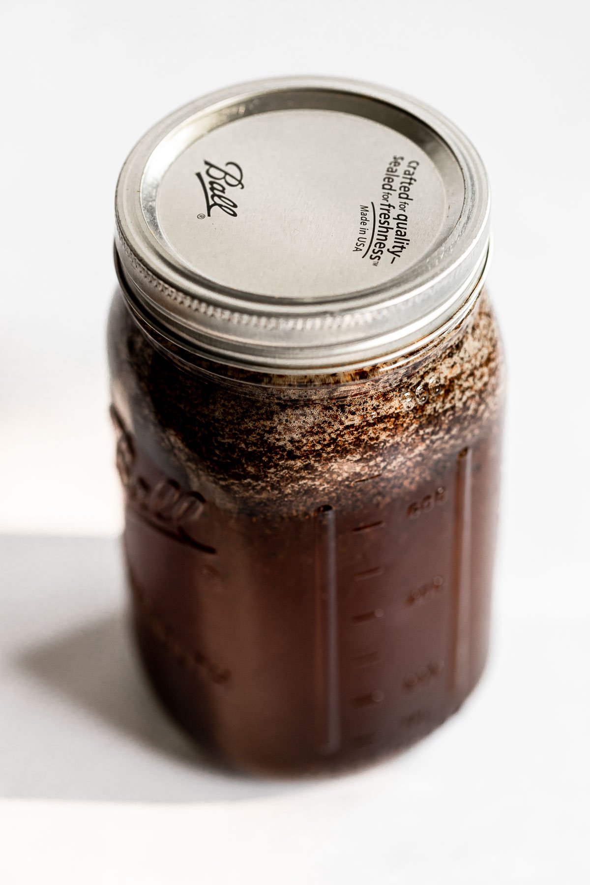 Jar with coffee grounds and water and lid on top.