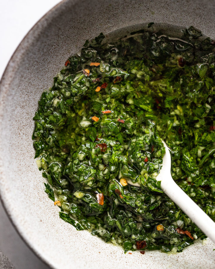 Up close bowl of chimichurri sauce with spoon.