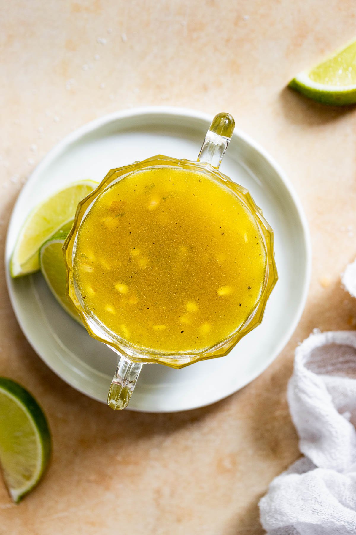 Glass bowl of honey lime dressing on white plate.