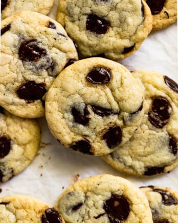 Pile of chocolate chip cookies on parchment paper.