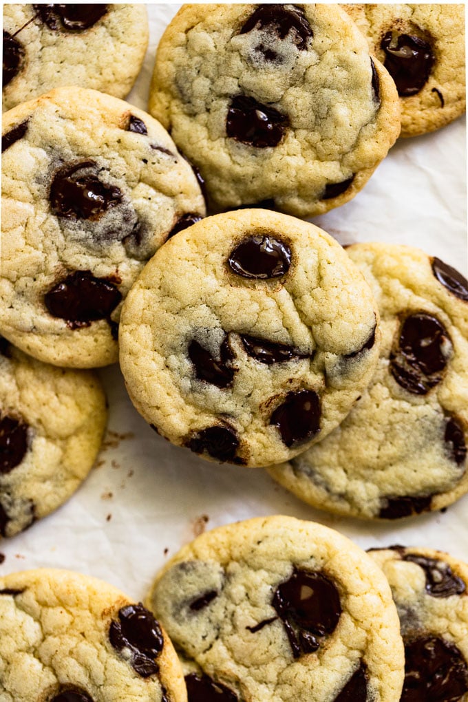 Pile of chocolate chip cookies on parchment paper.