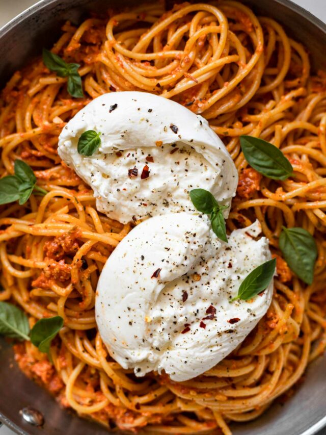 Burrata on top of pasta in a skillet.