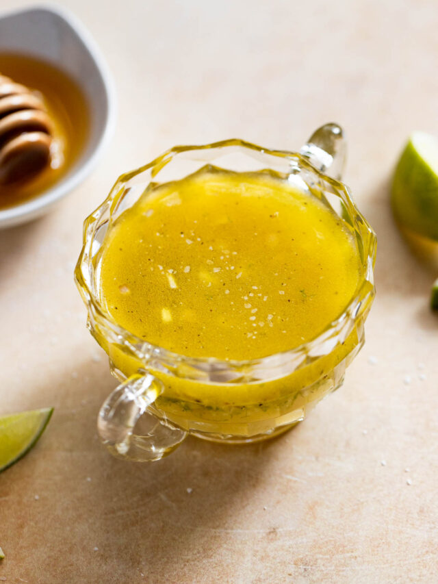 Honey lime dressing in glass jar next to limes and honey.