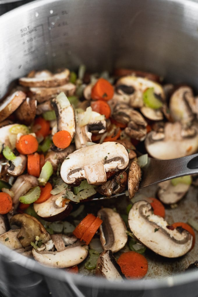Sliced mushrooms in pot with spoon.