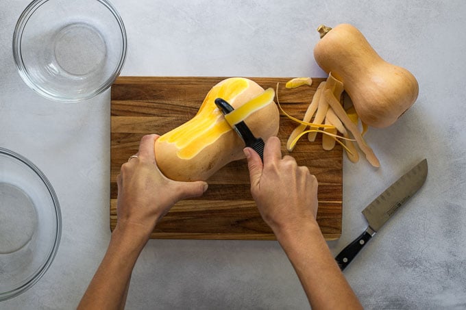 Peeling butternut squash on cutting board.