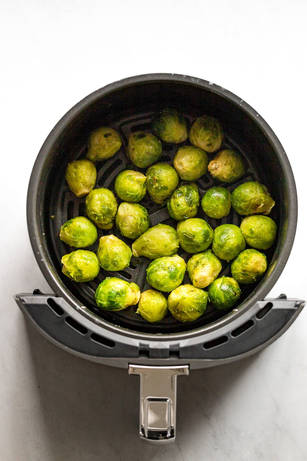 Brussels sprouts in air fryer halfway through cooking.