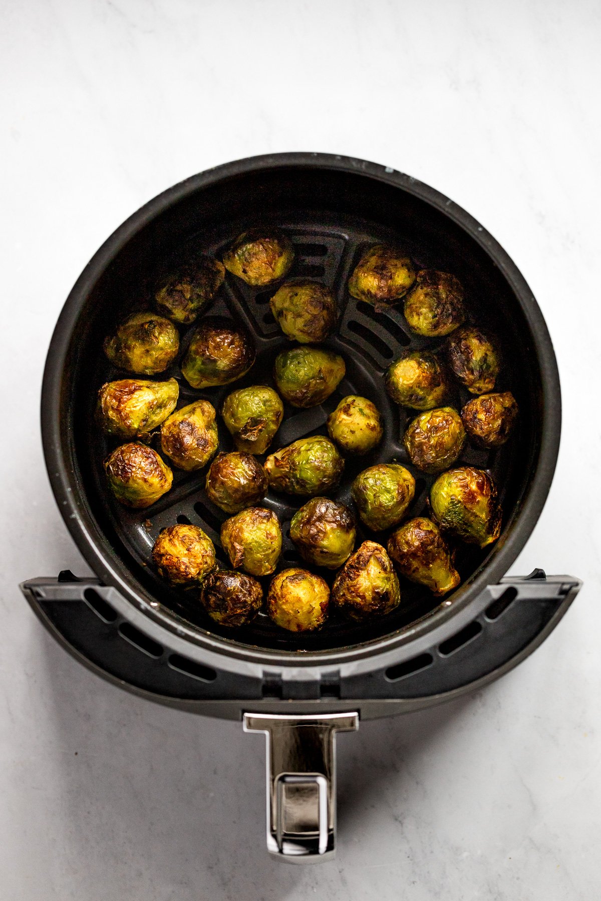 Brussels sprouts in air fryer after cooking with crispy exterior.