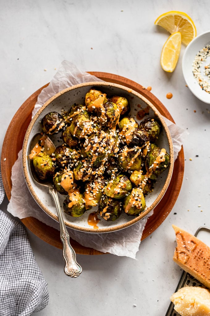 Bowl of brussels sprouts with tahini and seasoning on top.