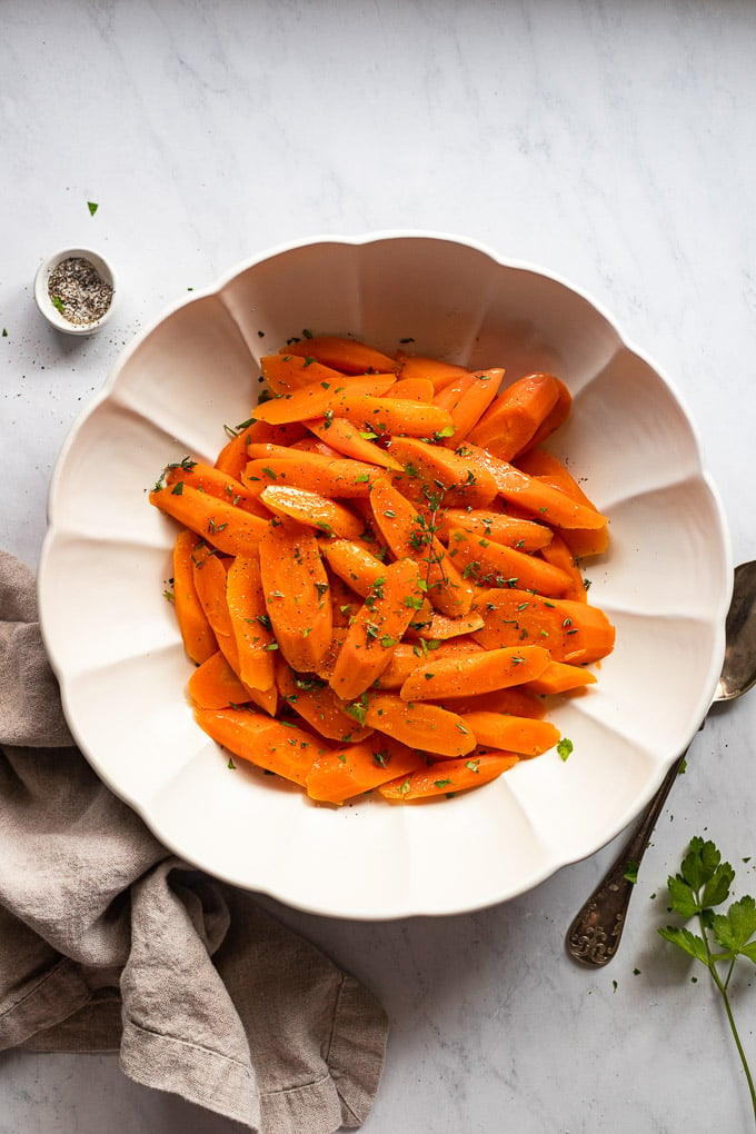Bowl of steamed carrots with herbs.