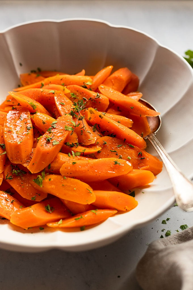 Bowl of cooked carrots with spoon.
