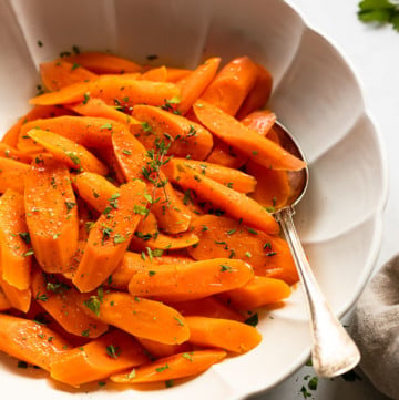 Bowl of steamed carrots with spoon.